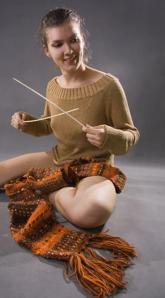 Η νεαρή γυναίκα πλέκει ένα κασκόλ. — Φωτογραφία Αρχείου