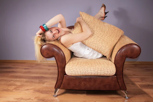 Cheerful young woman sits in an armchair — Stock Photo, Image