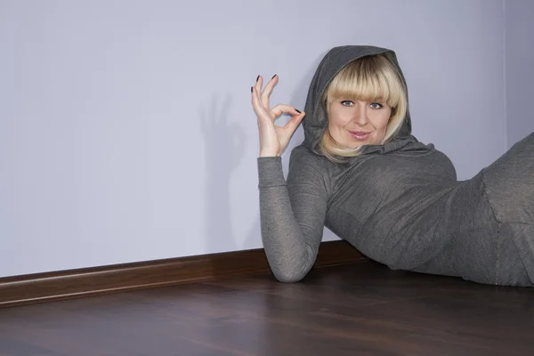 Fröhliche Frau gibt auf einem Fußboden das Okay-Zeichen — Stockfoto