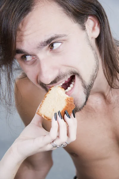 The young man eats a cake from female hands — Stock Photo, Image