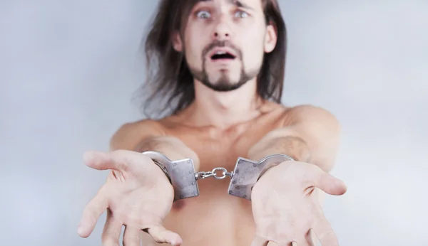 Chained in handcuffs long-haired caucasian guy