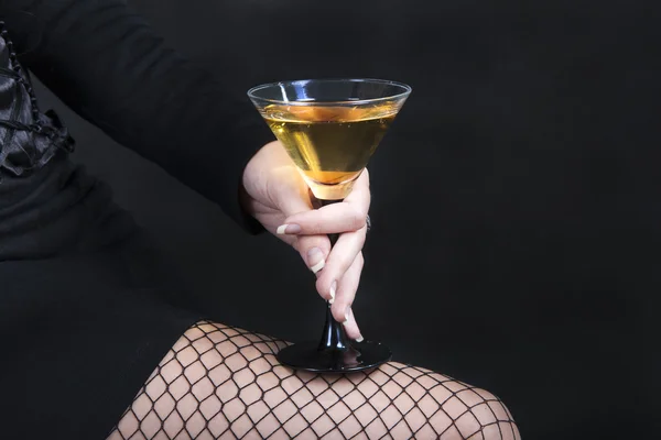 Den eleganta kvinnan håller en cocktail på en svart bakgrund Stockfoto