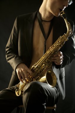 The young jazzman plaing a saxophone on black clipart