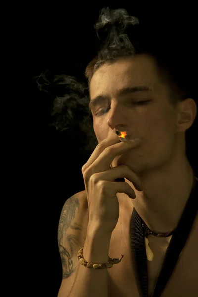การสูบบุหรี่ชายหนุ่มปิดตาของเขา — ภาพถ่ายสต็อก