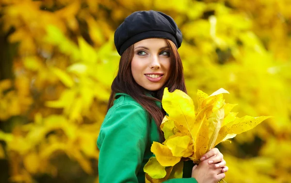 Модна жінка в осінньому парку тримає жовтий лист — стокове фото