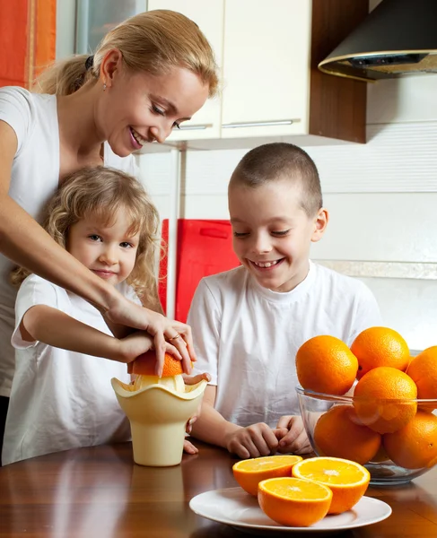 Matka s dětmi vymačkaná pomerančová šťáva — Stock fotografie