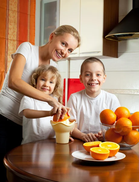 Matka z dziećmi wyciśniętego soku z pomarańczy — Zdjęcie stockowe
