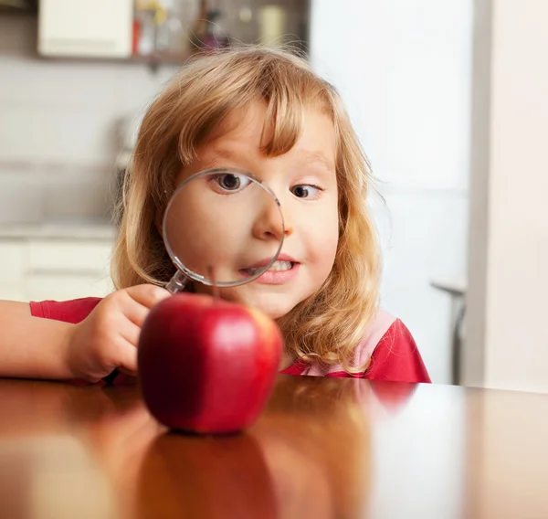 Barnet funderar ett förstoringsglas äpple — Stockfoto