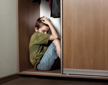 Sad boy, hiding in the closet clipart