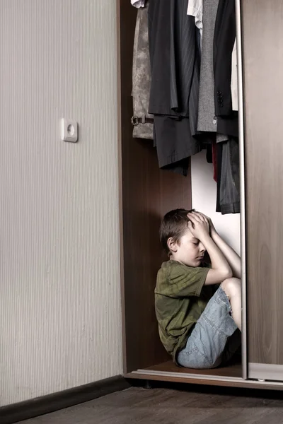 Rapaz triste, escondido no armário — Fotografia de Stock