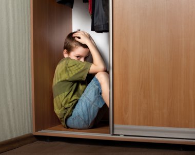 Sad boy, hiding in the closet clipart