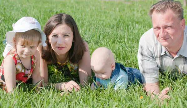 Familie van vier liggen op het gras — Stockfoto