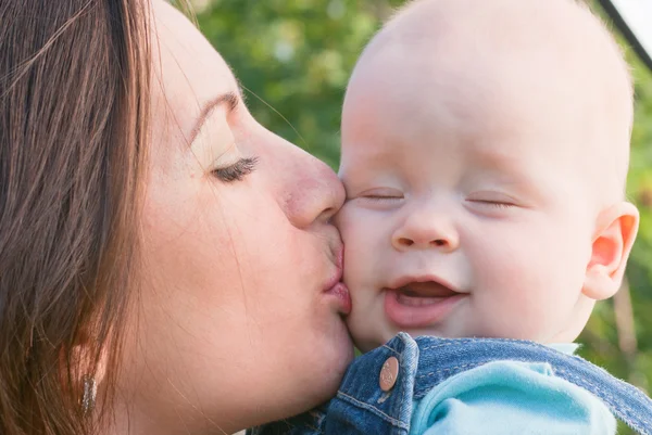 Mulher ternamente beija seu bebê na bochecha — Fotografia de Stock