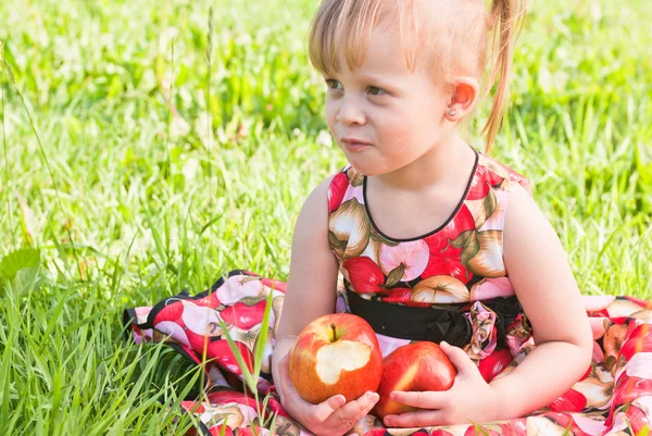 Дівчина сидить на траві з яблуками — стокове фото