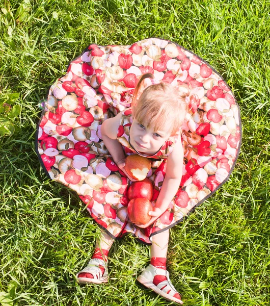 Meisje, zittend op het gras met appels — Stockfoto