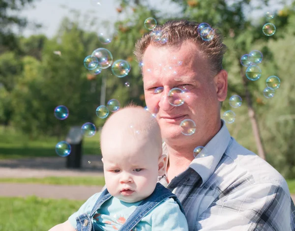 Папа и сын рассматривают мыльные пузыри — стоковое фото