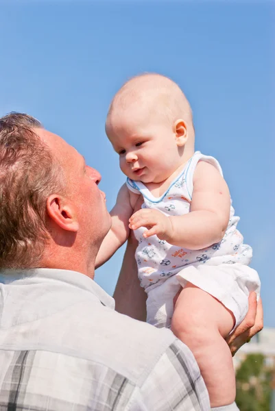 Pai segura seu bebê em seus braços, olhando um para o outro — Fotografia de Stock