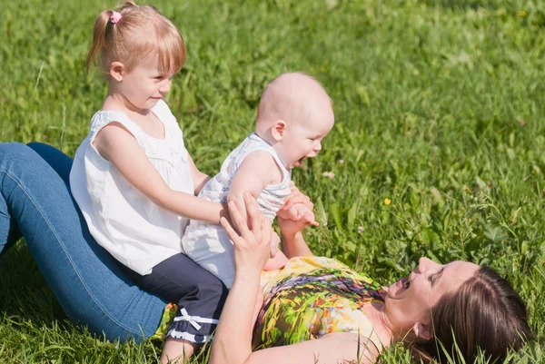 Matka z dwójką dzieci gra na trawie — Zdjęcie stockowe