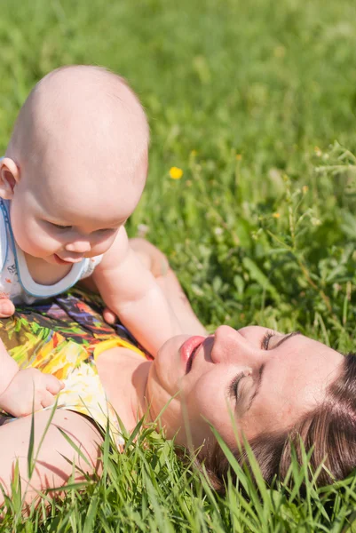 Мама и ребенок лежат на траве, играют — стоковое фото