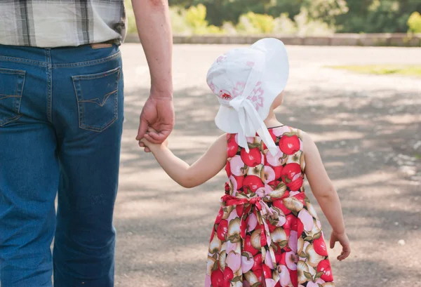 Chica en sombrero blanco y vestido va con la mano de su padre —  Fotos de Stock