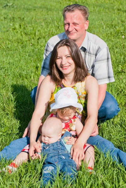 En lycklig familj av fyra på gräsmattan — Stockfoto