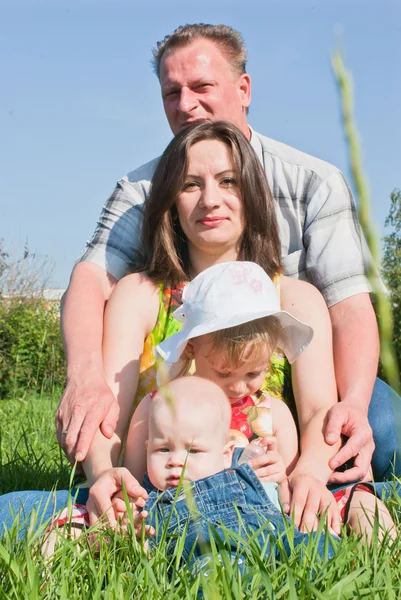 Une famille heureuse sur la pelouse, contre le ciel — Photo