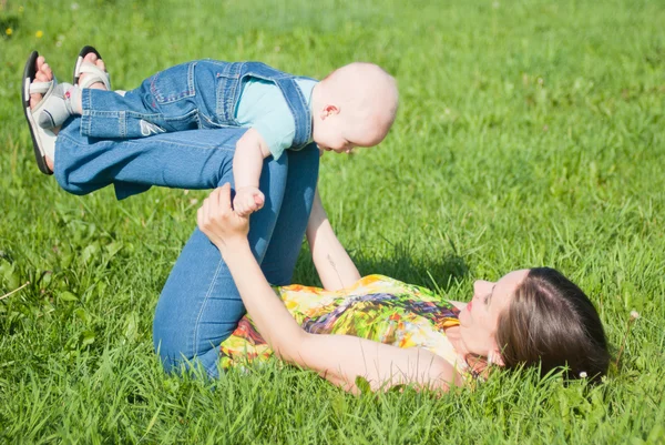 Мама делает зарядку с ребенком на траве — стоковое фото