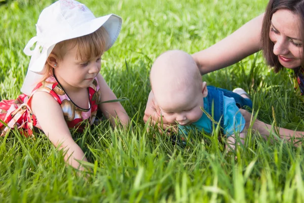 Mãe e filha brincando com um bebê na grama — Fotografia de Stock
