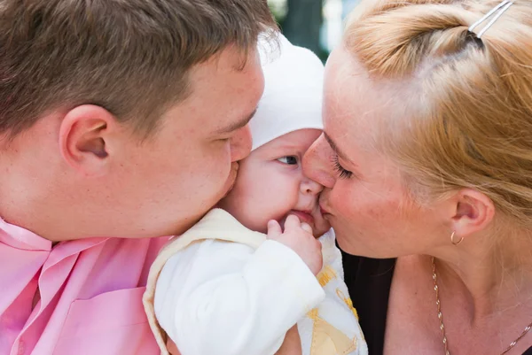Mère et père embrassant la joue du bébé — Photo