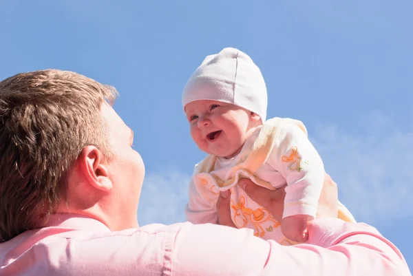 Papai levanta seu bebê alegre alto sobre um — Fotografia de Stock