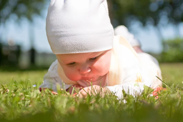 Маленький ребенок ползает по зеленой траве — стоковое фото