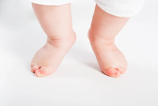 Pequenas pernas da criança em um fundo branco — Fotografia de Stock