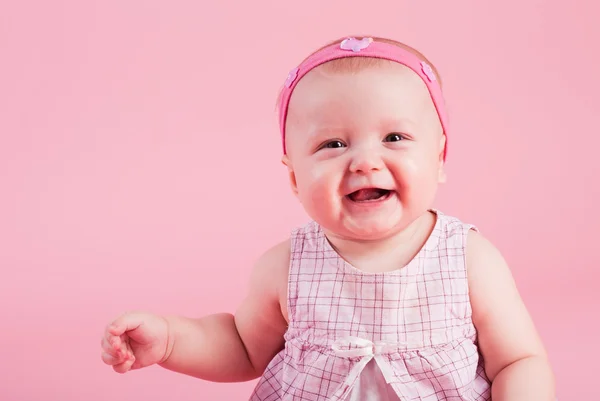 A pequena menina sorridente bonita em um fundo rosa — Fotografia de Stock