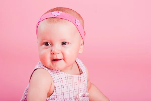 Retrato da pequena bela menina alegre em um fundo rosa — Fotografia de Stock