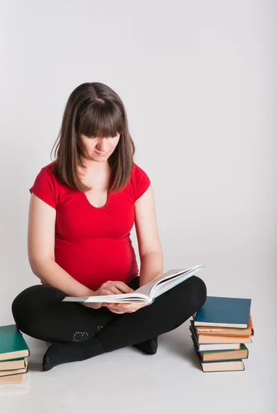 The pregnant woman reads many books — Stock Photo, Image