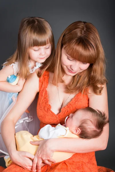 Mamá con una hija mira al recién nacido —  Fotos de Stock