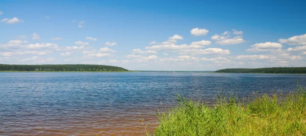 Lake landschap met heuvels en blauwe bewolkte hemel — Stockfoto
