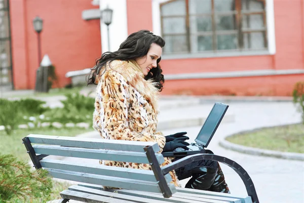 Brunette met laptop outdoors — Stockfoto