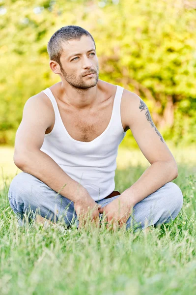 黑头发的女人坐草の上に座っている若い男 — ストック写真