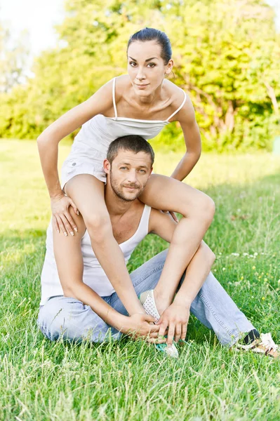 Joven hermosa pareja se sienta en la hierba —  Fotos de Stock