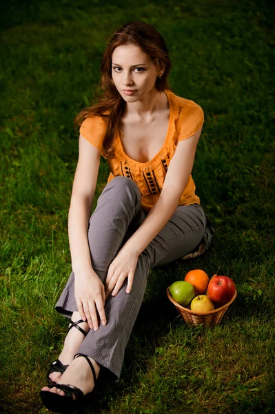 Krásná dívka sedí na zelené trávě — Stock fotografie