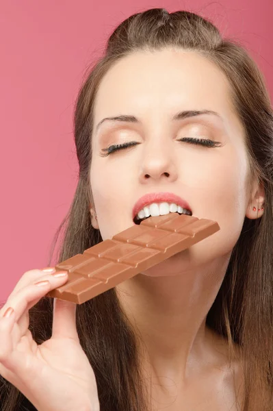 Junge Frau beißt in Schokolade — Stockfoto
