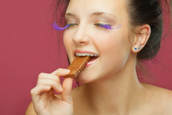 若い女性はチョコレートからオフをかむ — ストック写真