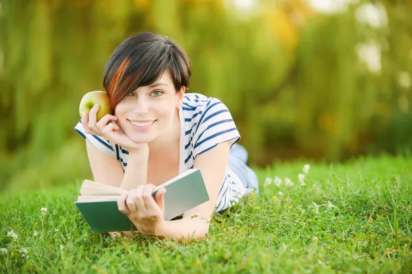 Девочка лежит на траве и читает книгу — стоковое фото