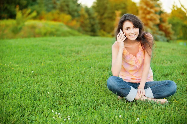 Žena sedí na zeleném trávníku — Stock fotografie