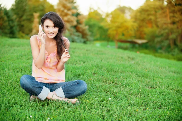 女人坐在绿色的草坪上 — 图库照片