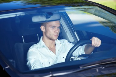 Attractive man behind the wheel of his car clipart