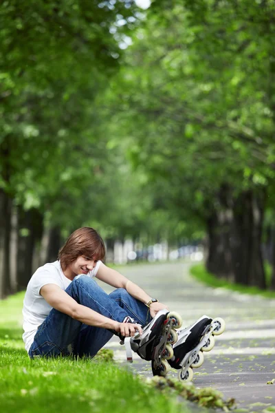 Молодой Парень Закрепляет Ролики Траве Парке — стоковое фото