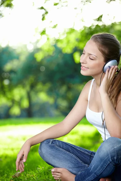 Μια Νεαρή Κοπέλα Ακούει Μουσική Ακουστικά Στο Πάρκο — Φωτογραφία Αρχείου