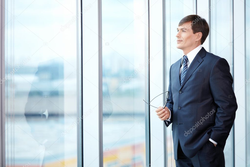 A man in a business suit looks out the window